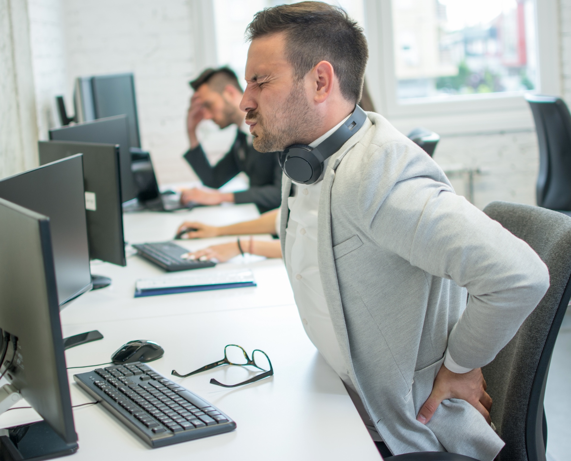 Office employee experiencing back pain at his desk